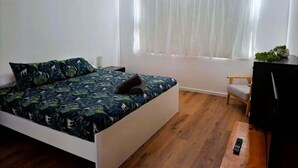 A bedroom with a bed, a window with curtains, a desk with a chair, and a television. - Holiday house for the whole family (Portland North)