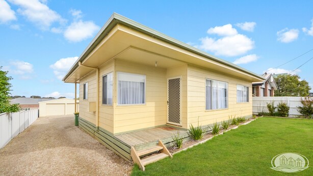 A single-story mobile home with a front porch, a small front yard, and a clear blue sky. - Holiday house for the whole family (Portland North)