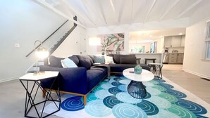 Ett modernt vardagsrum med en blå soffa, två sidobord, ett soffbord och en mönstrad matta.