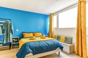 Un dormitorio con cama, mesita de noche, ventana y vistas al exterior.