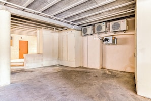 An empty room with concrete floors, beige walls, and three air conditioning units mounted on the wall.