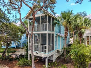A two-story building with a balcony, surrounded by trees and vegetation.