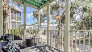 A covered porch with wicker furniture and a view of neighboring houses. - Mermaid's Rest Steinhatchee Landing Resort - Sleeps 6 (Steinhatchee)