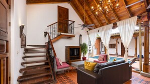 A spacious living area with a staircase, a sofa, a television, and a pool area. - Casa Leon - colonial home with indoor pool (Tamarindo)