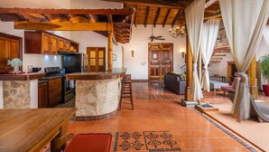 A spacious kitchen with a central island, wooden cabinets, and a stone countertop. - Casa Leon - colonial home with indoor pool (Tamarindo)