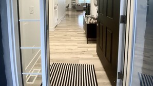 Un interior modern amb una entrada amb porta de vidre, una cuina amb taula de dinar, i un passadís que condueix a una zona d'estar.
