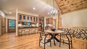 A spacious kitchen with wooden cabinets, a central island, and a dining area with a round table and chairs. - Secluded Sapphire Chalet w/ Game Room + Decks (Sapphire)