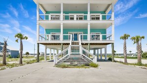 A multi-story beachfront house with a central staircase, two balconies, and a covered outdoor area. - Seas the Day-Gulf View Private Pool Home Across the Street from the Beach (Navarre)