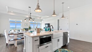 A spacious kitchen with white cabinetry, a large island, and pendant lighting. - Seas the Day-Gulf View Private Pool Home Across the Street from the Beach (Navarre)