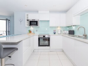 A modern kitchen with white cabinets, a microwave, oven, and a sink.