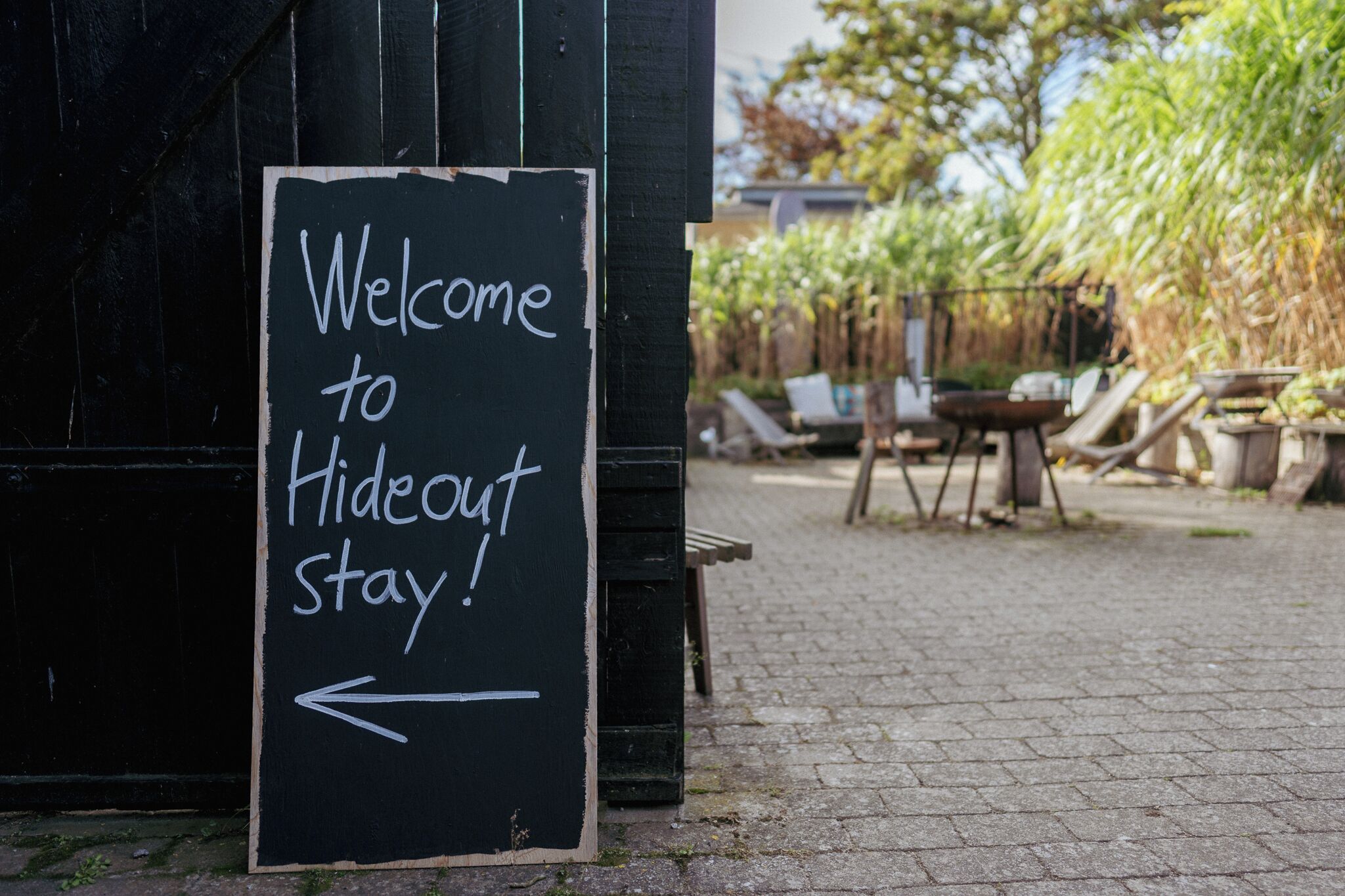 A sign reading "Welcome to Hideout Stay!" with an arrow pointing left.