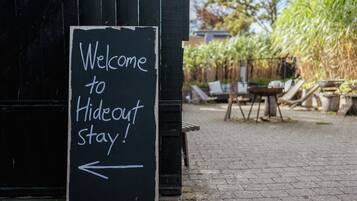 A sign reading "Welcome to Hideout Stay!" with an arrow pointing left.