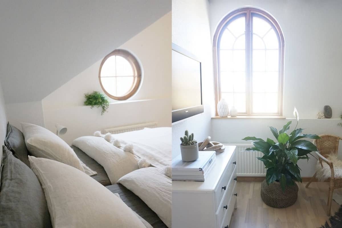 A bedroom with a bed, a round window, a radiator, and a potted plant.