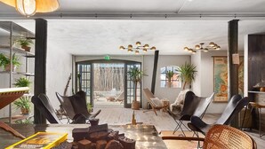 A spacious lounge area with modern furniture, a large window, and a view of the outdoor seating area. - Kåseberga Hideout (Loderup)