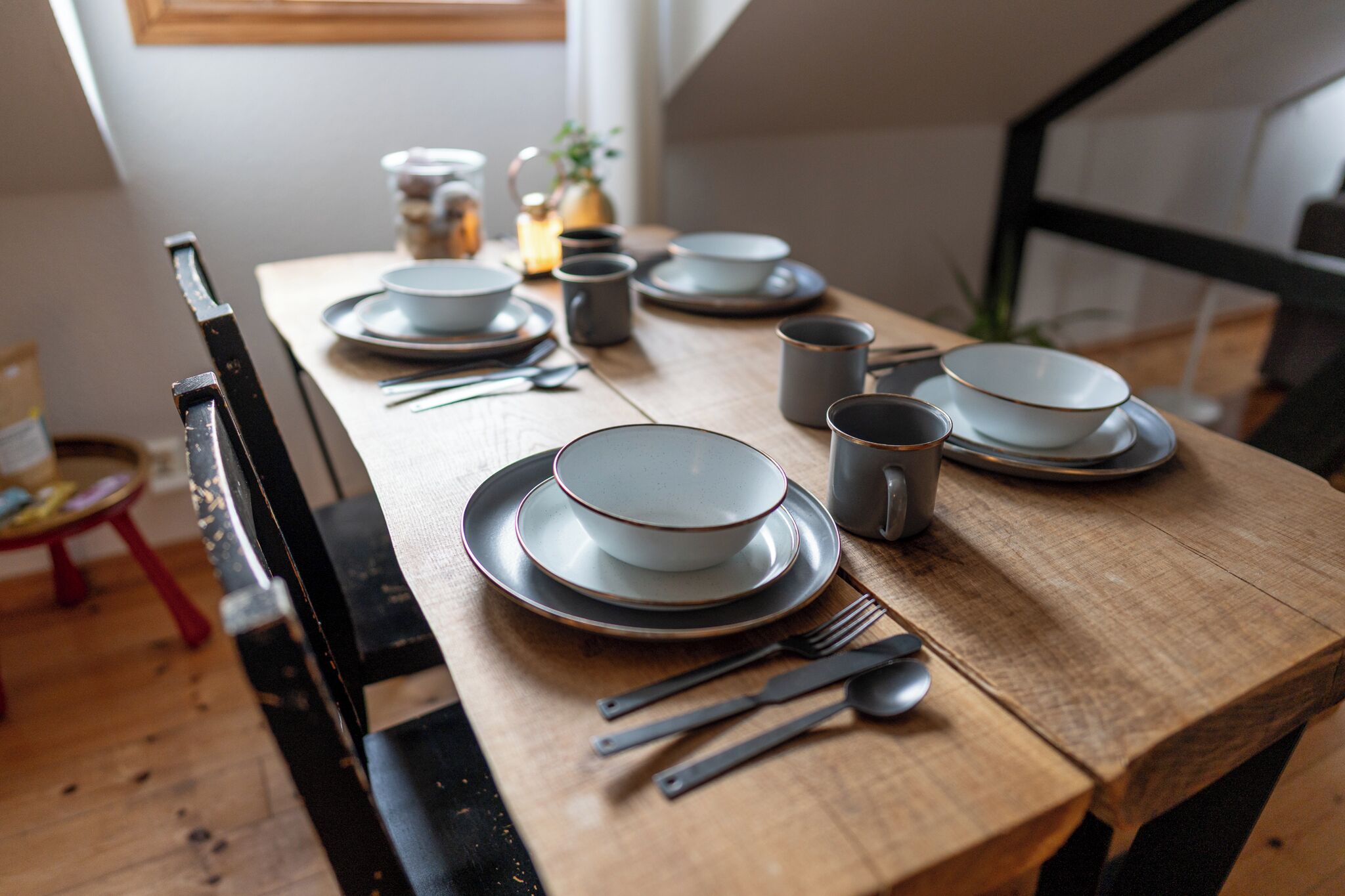 Una mesa de comedor dispuesta con platos, tazones, vasos y cubiertos.