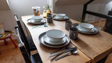 Una mesa de comedor dispuesta con platos, tazones, vasos y cubiertos.