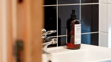 A bathroom with a white sink, a bottle of lotion, and black and white tiled walls.