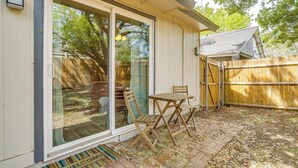 A patio with a sliding glass door, a small table, and two chairs.