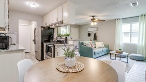 A modern kitchen with white cabinets, a built-in oven, and a dining area with a round table and chairs.