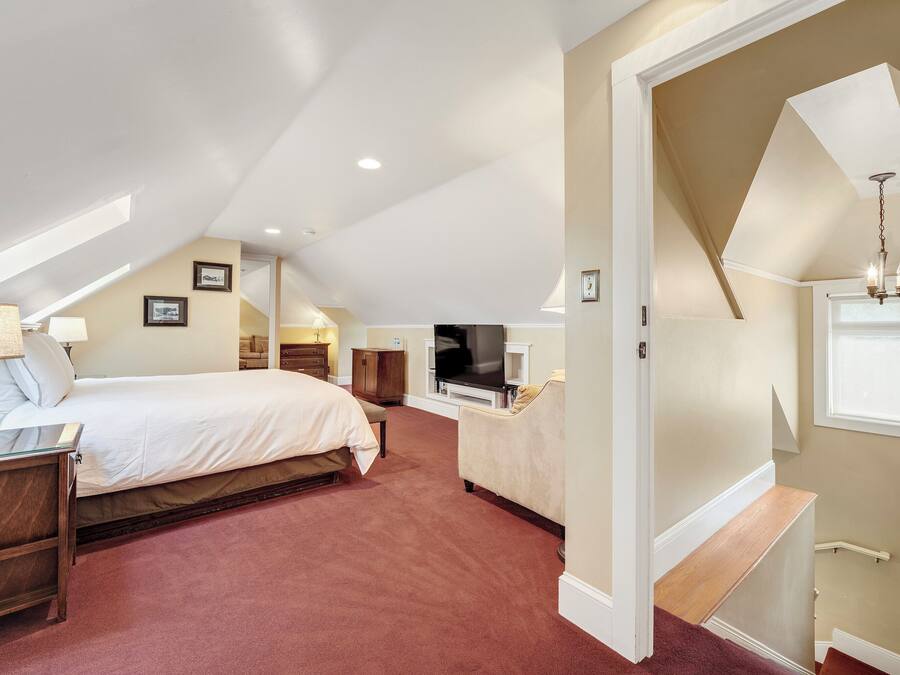 Quarto de hotel com uma cama, uma escrivaninha, uma televisão e uma janela.