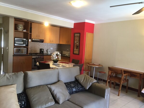 A compact living space with a kitchenette, a dining area, and a seating area with a sofa and chairs.
