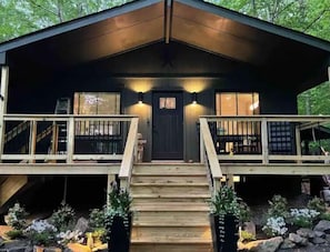 Une cabane dotée d’une terrasse en bois, d’une porte d’entrée et de deux fenêtres.