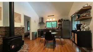 A modern kitchen with a central island, a dining area with chairs, and a fireplace. - Saturdays Cabin, Hot Tub, Hammock, Gas Firepit (pocono lake)