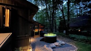 A cozy cabin with a hot tub surrounded by a stone pathway and forest. - Saturdays Cabin, Hot Tub, Hammock, Gas Firepit (pocono lake)