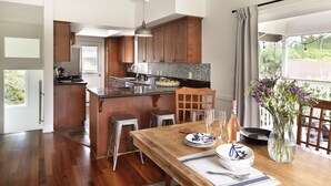 Una cocina moderna con armarios de madera, una isla central y un comedor con una mesa preparada para dos.