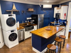 Une cuisine compacte dotée d’un îlot central en bois, d’appareils électroménagers intégrés et d’un mur d’accent bleu.
