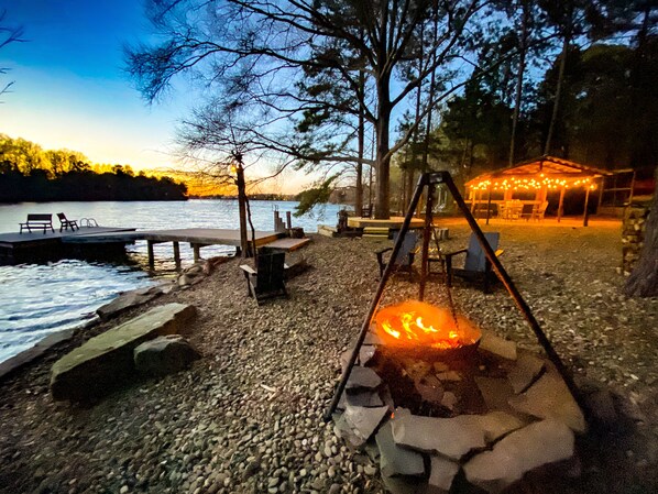 Une terrasse au bord du lac, avec un foyer, des sièges et un quai.