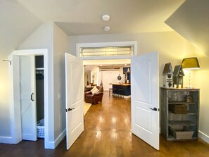 Une porte ouverte donne sur un salon doté d’un plancher en bois, avec un coin repas et une cuisine à l’arrière-plan.