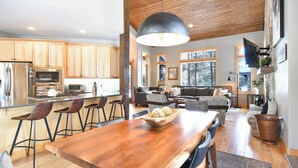 Una cocina moderna con armarios de madera, una isla grande con taburetes de bar y una mesa de comedor.