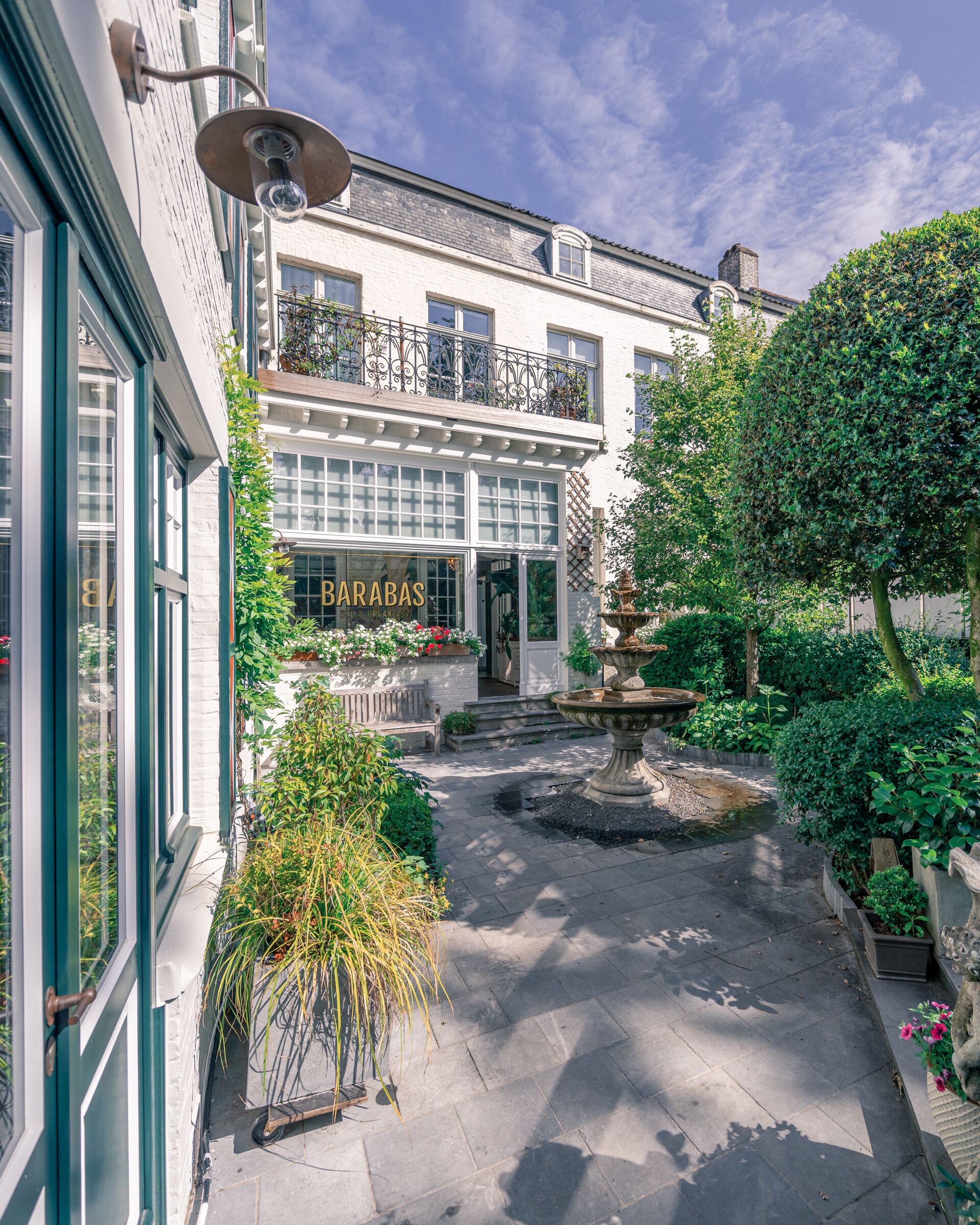 A courtyard with a fountain, a bar named "BARABAS," and a building with a balcony.