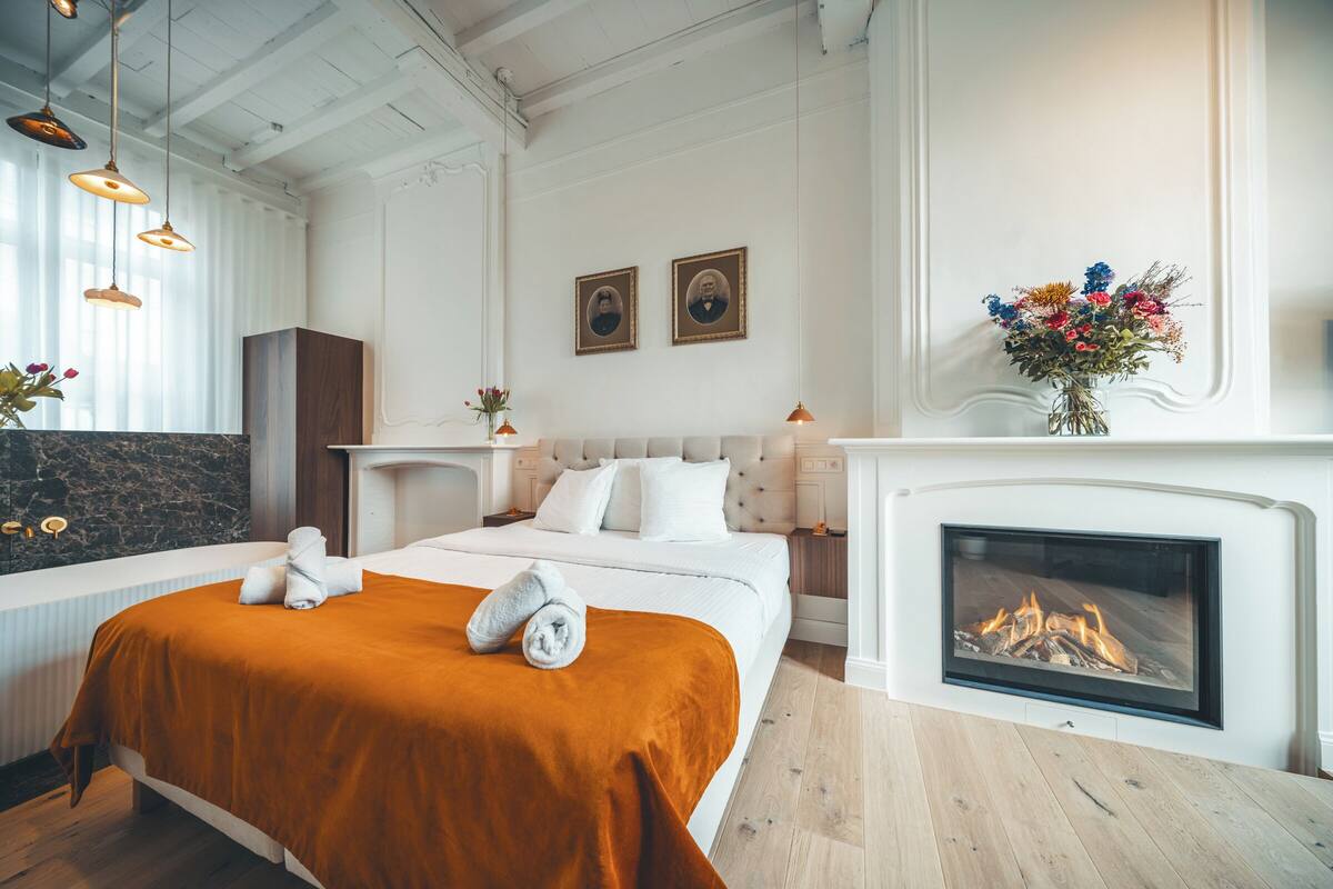 Ett hotellrum med en stor säng, en öppen spis och utsikt över elden.