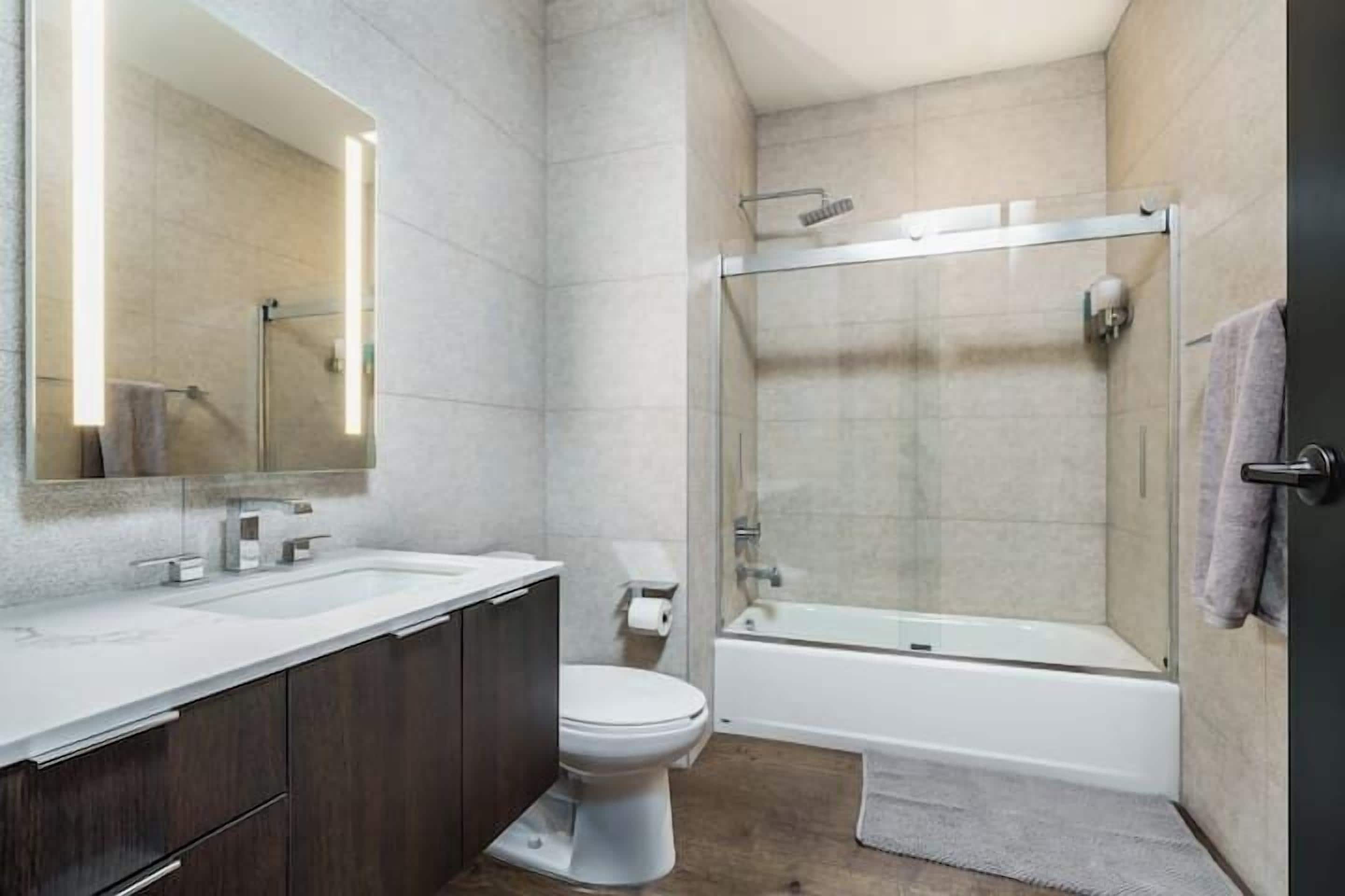 A modern bathroom with a glass-enclosed shower, a white sink, and a dark wooden vanity.