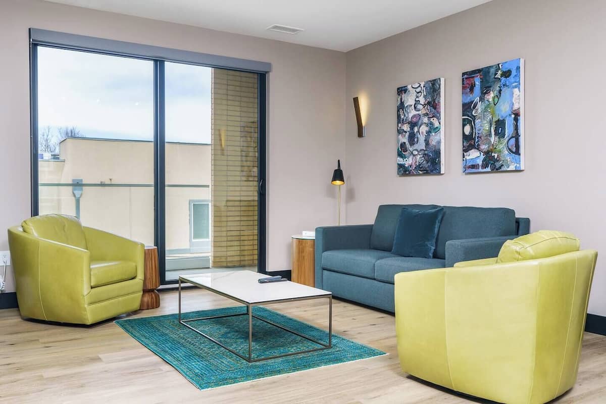 Uma sala de estar moderna com sofá, duas poltronas, uma mesa de centro e obras de arte na parede.