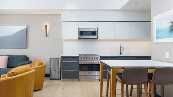 A modern kitchen with built-in appliances, a dining area with a table and chairs, and a sofa in the living area.
