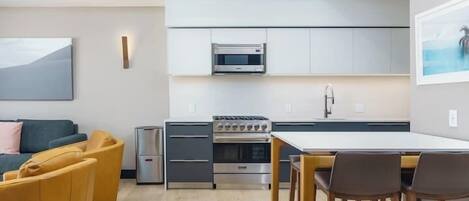 A modern kitchen with built-in appliances, a dining area with a table and chairs, and a sofa in the living area.