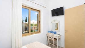 Une chambre à coucher avec un lit, un bureau et une chaise, une télévision et une porte.