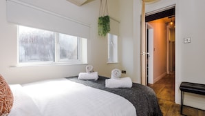 A hotel room with a large bed, two rolled towels, a hanging plant, and a bench. - 4 Bed Urban Home in Manchester (Manchester)