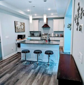 Enjoy cooking in this well-equipped kitchen with a central island, white cabinetry, and stainless steel range hood.