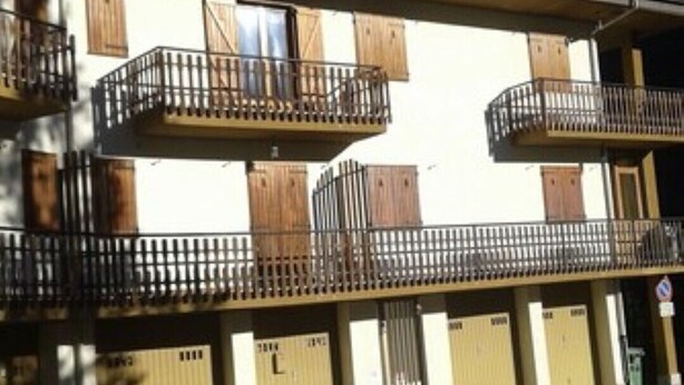 A multi-story building with balconies, wooden shutters, and a garage entrance. - Furnished mini-apartment (Bagni di Vinadio)