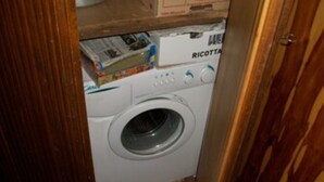 A compact laundry room with a front-loading washing machine and a dryer. - Furnished mini-apartment (Bagni di Vinadio)