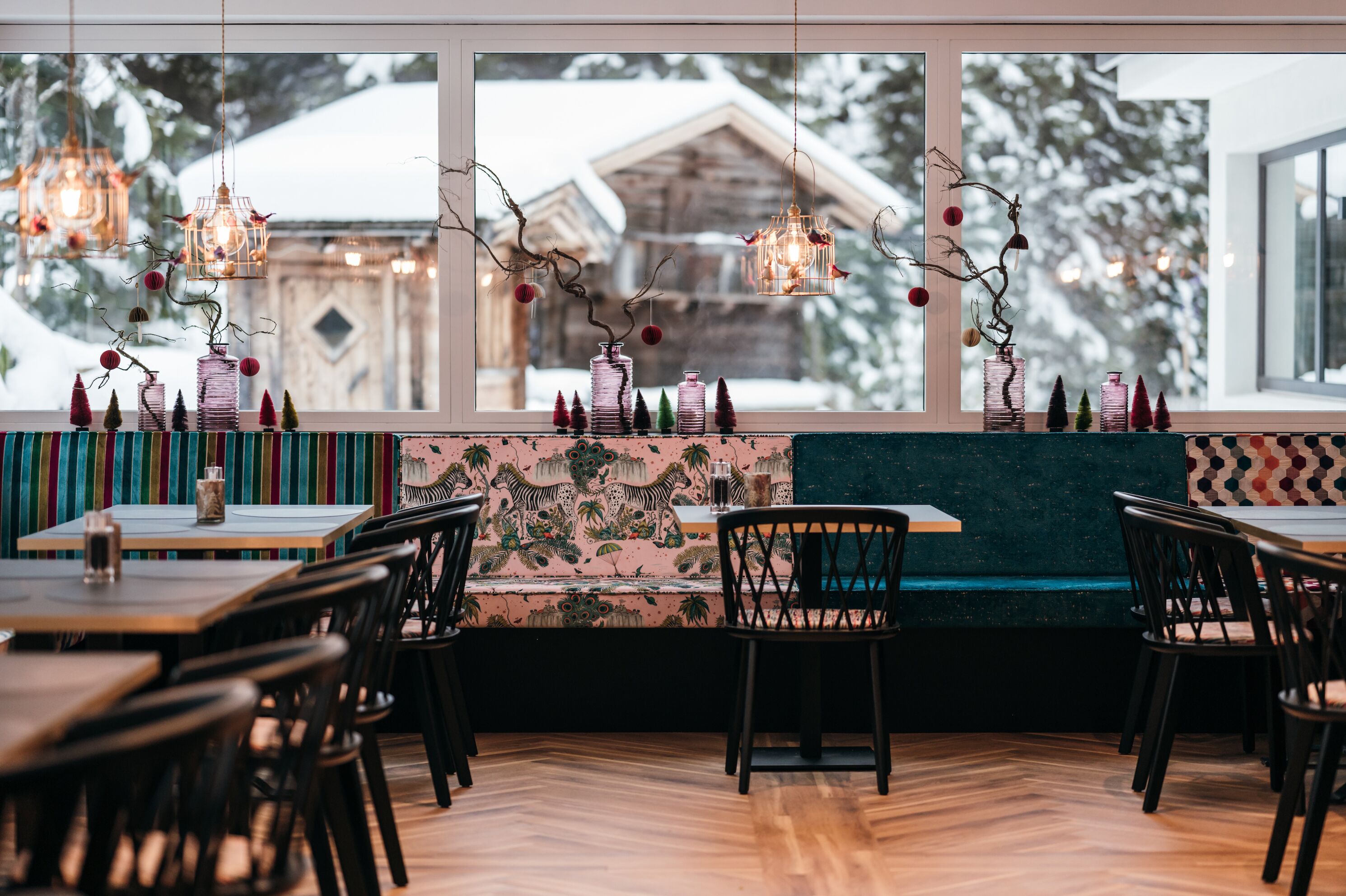 Un restaurante acogedor con mesas y sillas de madera, un muro colorido con motivos florales y faroles colgantes.
