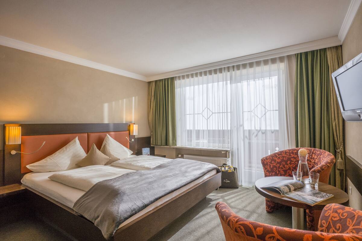 Une chambre d’hôtel avec un lit, un bureau, une chaise et un téléviseur.