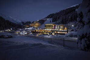 En snötäckt bergsanläggning med upplysta byggnader och en skidbacke.