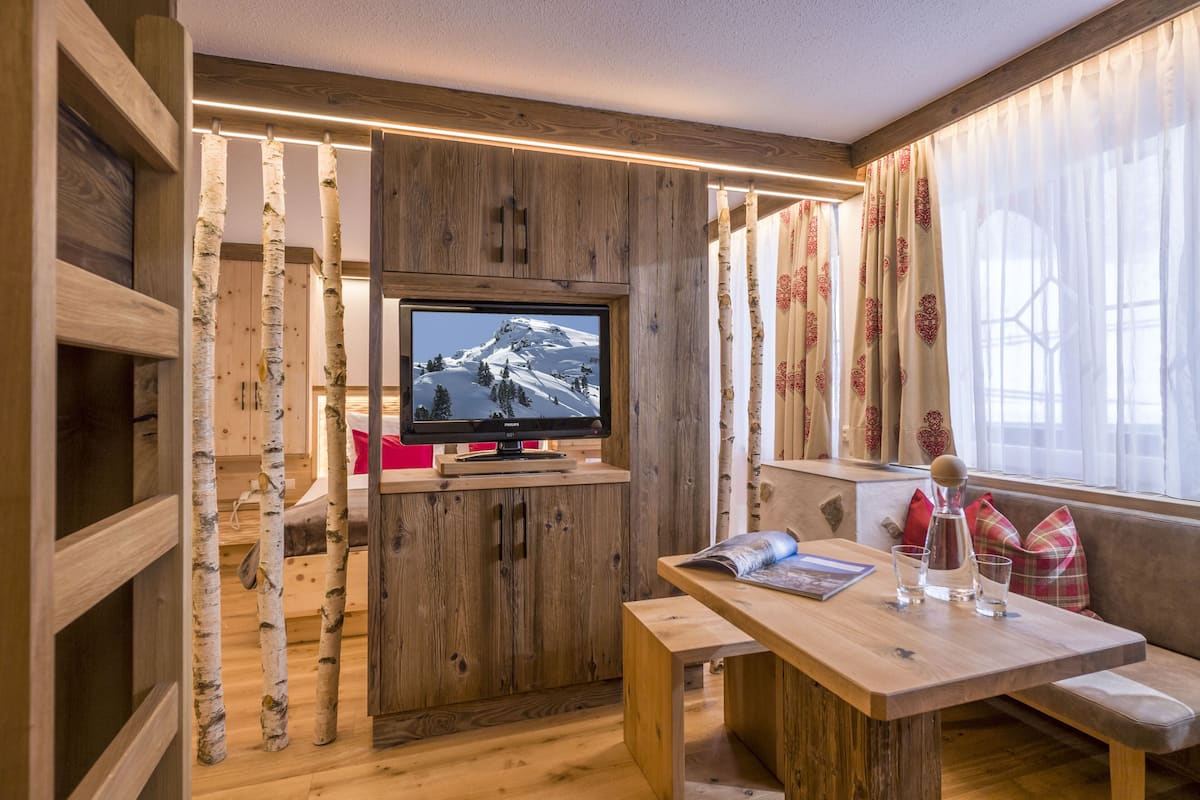 Une pièce chaleureuse avec un meuble TV en bois, un banc et une fenêtre avec des rideaux.