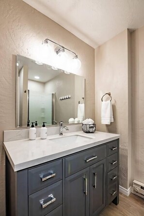 A bathroom with a large mirror, two sinks, and a towel rack.