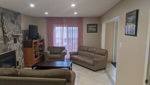 A living room with a stone fireplace, a television, a sofa, a loveseat, and a coffee table. - Cozy Waterfront on Puslinch Lake (Puslinch)